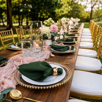 Elegant outdoor dining table set with gold accents and floral centerpiece.