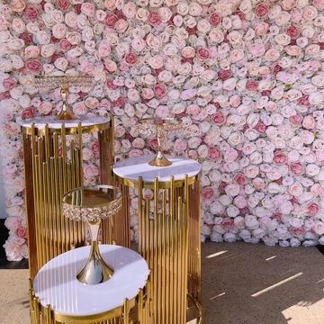 Elegant gold and white stands with a rose flower wall backdrop.