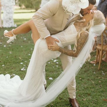 Newlyweds share a romantic kiss outdoors with the groom dipping the bride.