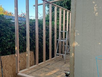 Wooden frame structure being built outdoors near a ladder.