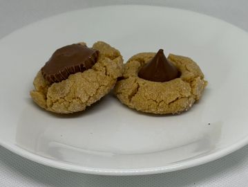 Two peanut butter cookies topped with chocolate pieces on a white plate.