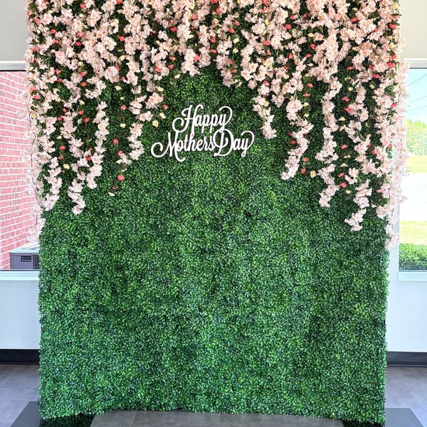 Mother's Day floral backdrop with greenery and hanging flowers.