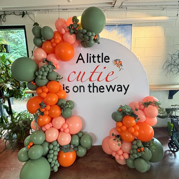Balloon arrangement with baby announcement backdrop.