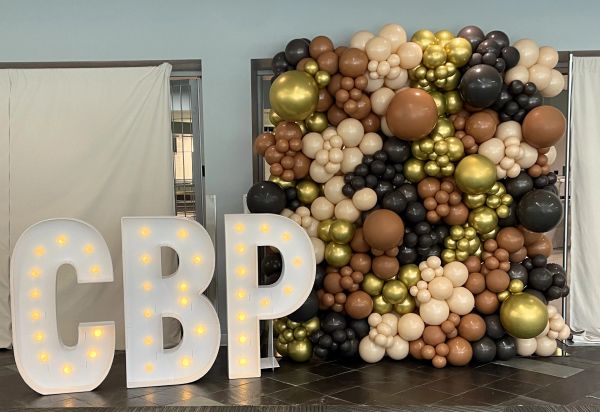 Large illuminated 'CBP' letters and a balloon backdrop.