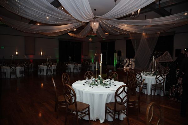 Elegant event space with draped ceiling and decorated tables.