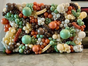 Colorful balloon wall with earth tones and green shades.