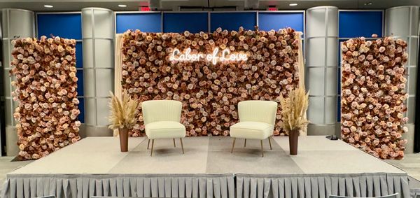 Elegant stage with floral backdrop and 'Labor of Love' sign.