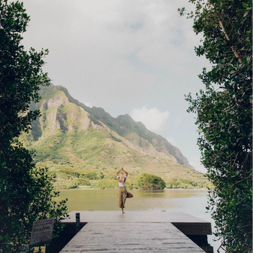 Yogi practicing on a dock by the lake and mountains