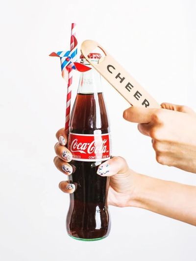a person holding a coca cola bottle with custom bottle opener