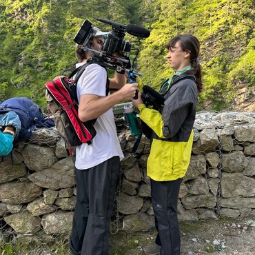 2 people standing with camera equipment