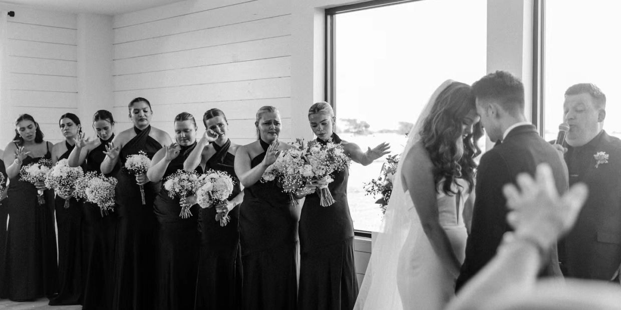 Bridesmaids praying during a wedding ceremony indoors.