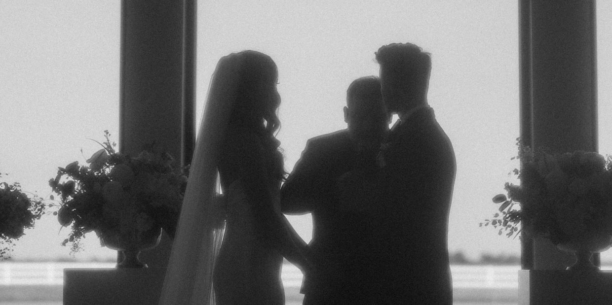Silhouetted bride and groom at wedding altar.