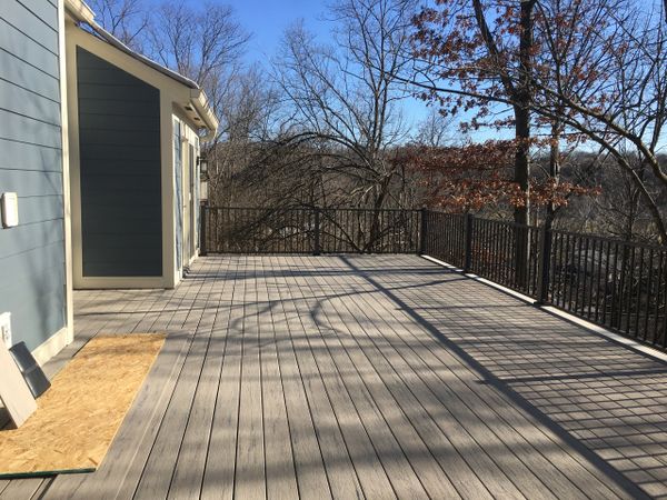 Spacious outdoor wooden deck with metal railing and clear blue sky.