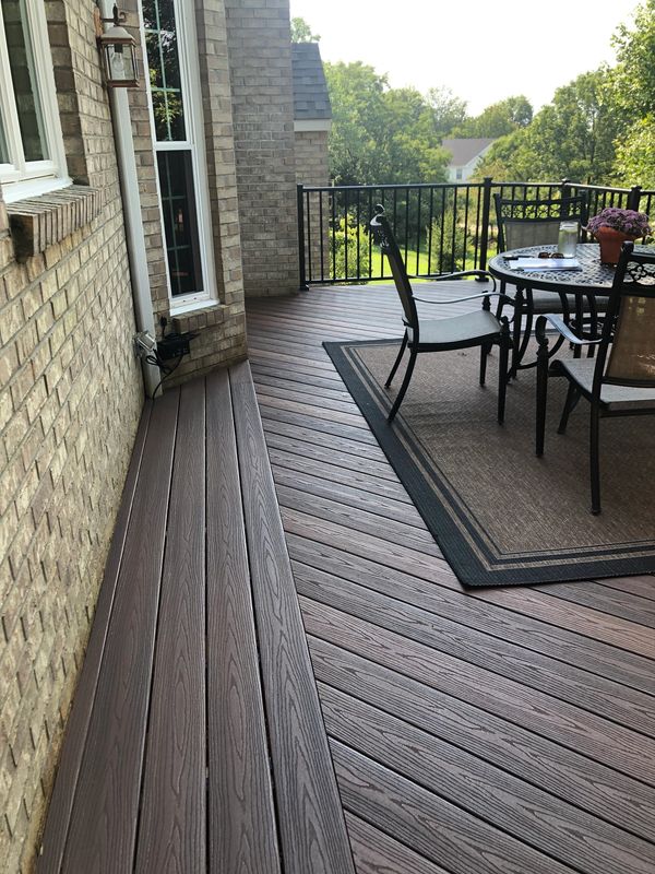 Elegant wooden deck with outdoor dining set and scenic backyard view.