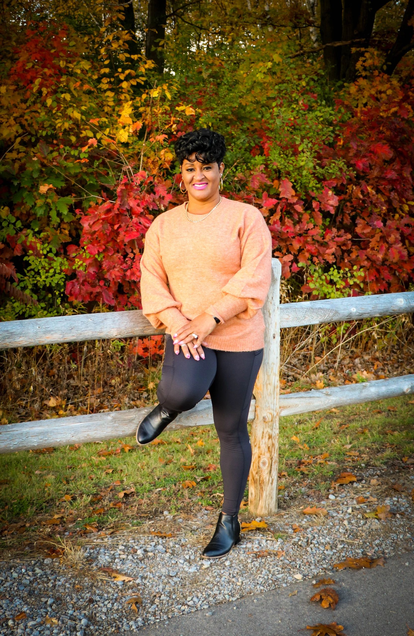 women leaning against wood fence