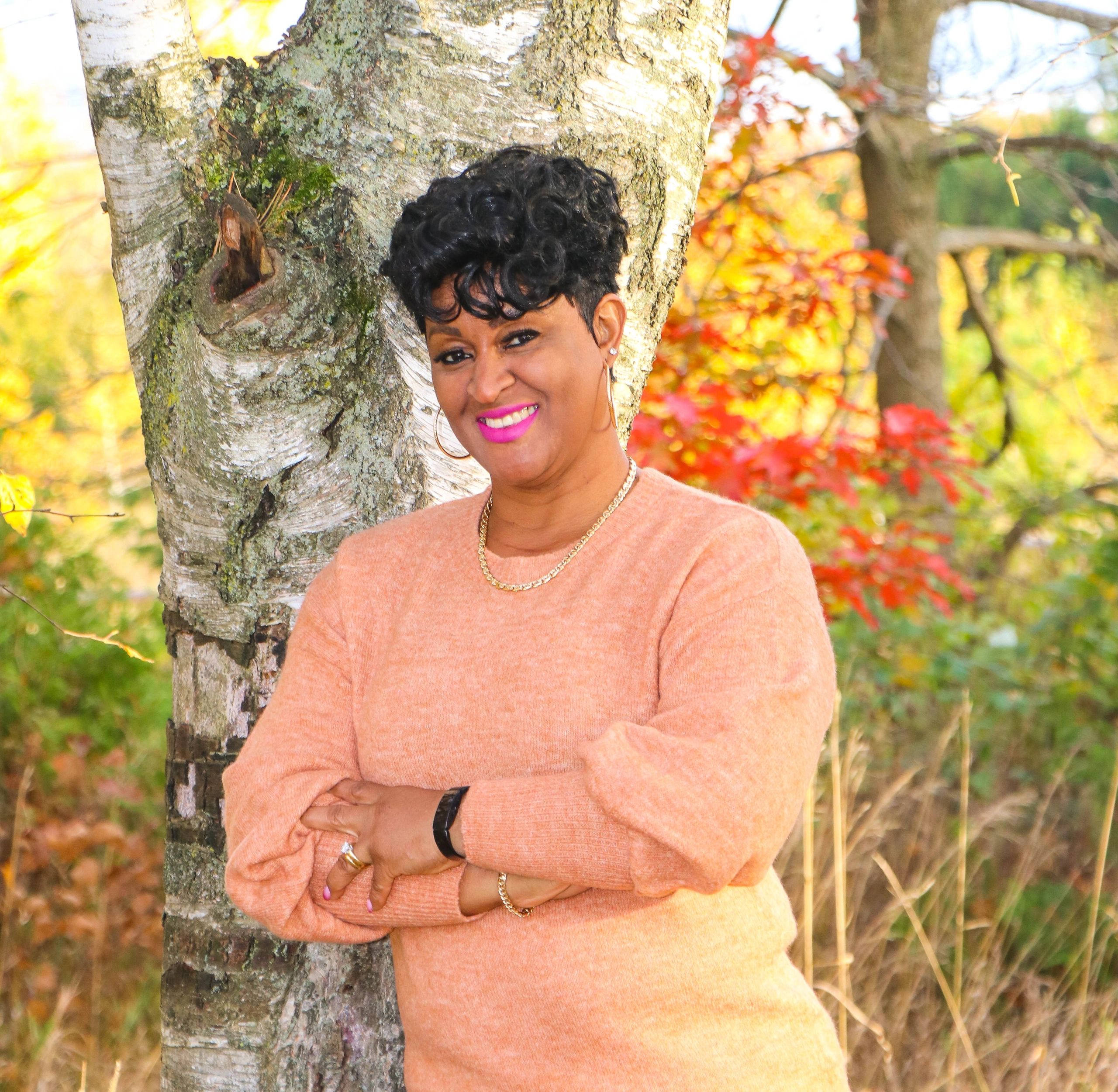 headshot of a lady leaning against a tree