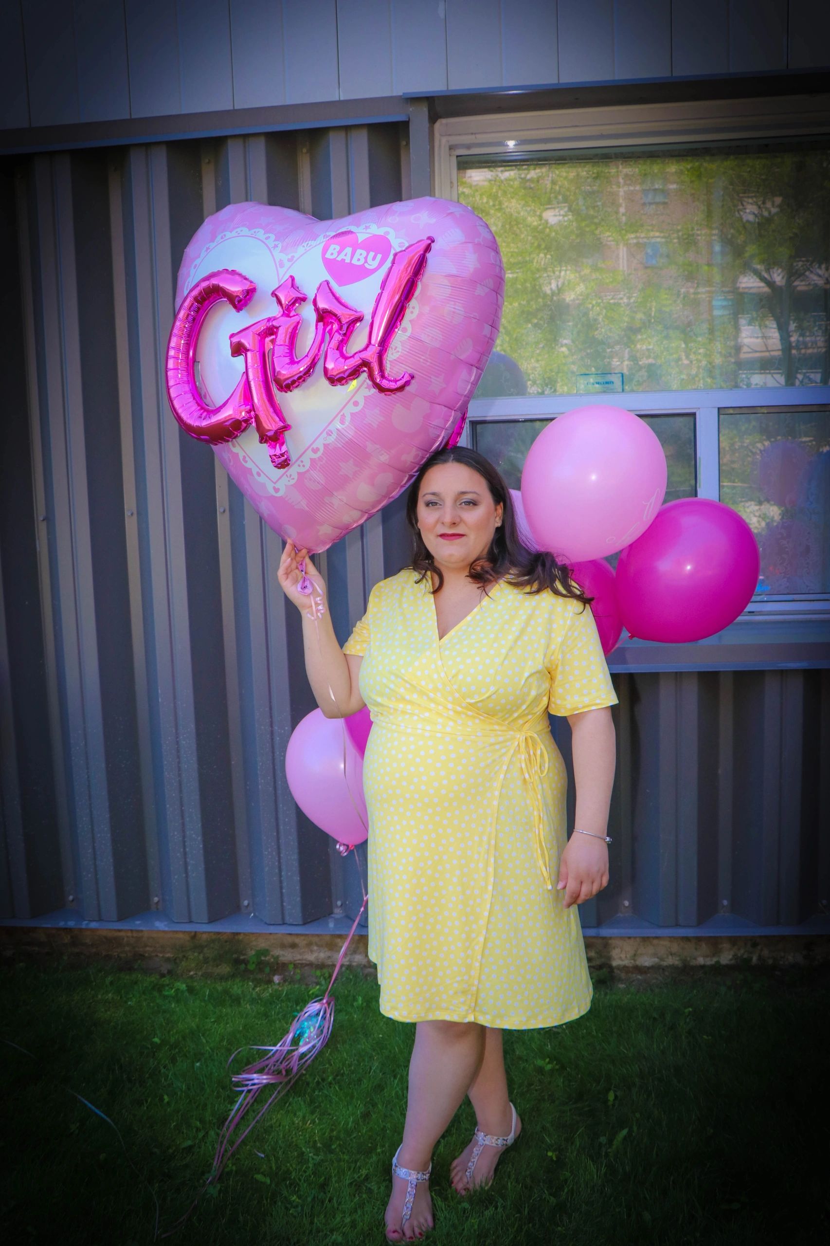 expecting mom holding its a girl balloon