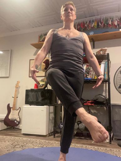 Person practicing yoga balancing on one leg indoors.
