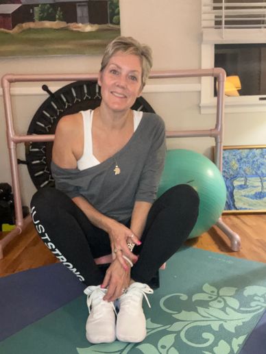 Woman sitting on yoga mat, smiling.
