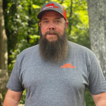 Man with a long beard in a gray t-shirt and a red cap.