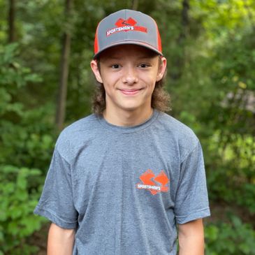 Teenage boy outdoors wearing a Sportsman's Warehouse hat and t-shirt.
