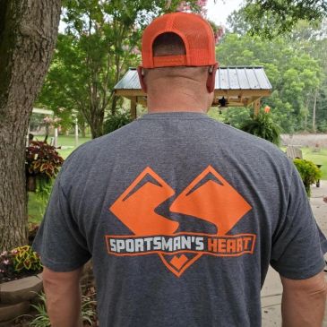 Man wearing a gray t-shirt with an orange Sportsman's Heart logo on the back.