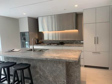 Modern kitchen with marble island and bar stools.
