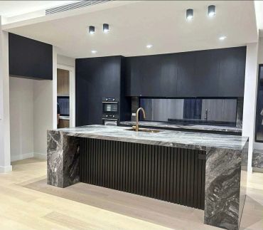 Modern kitchen with black cabinetry and marble island.