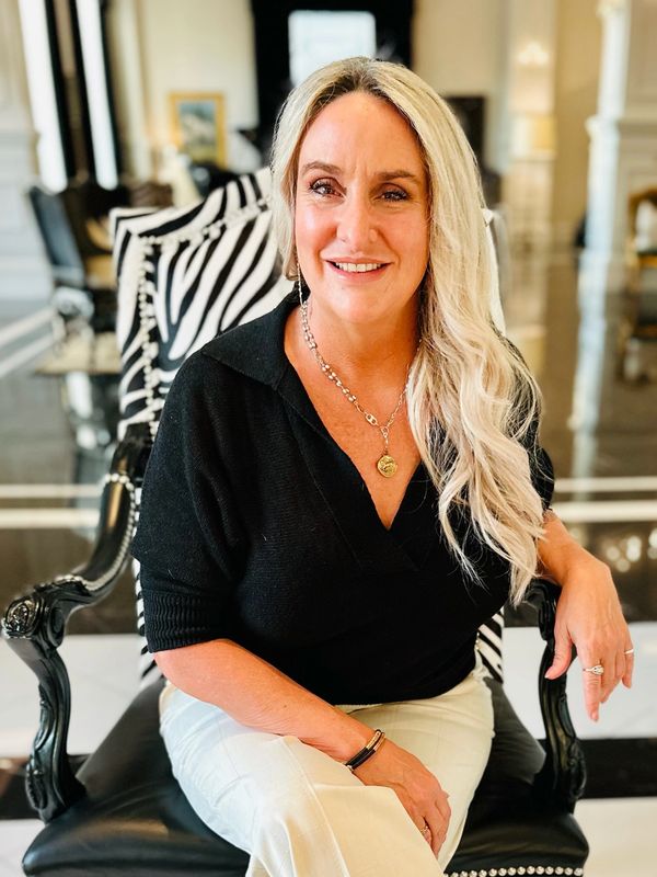 Blonde woman sitting and smiling on a black and white chair.