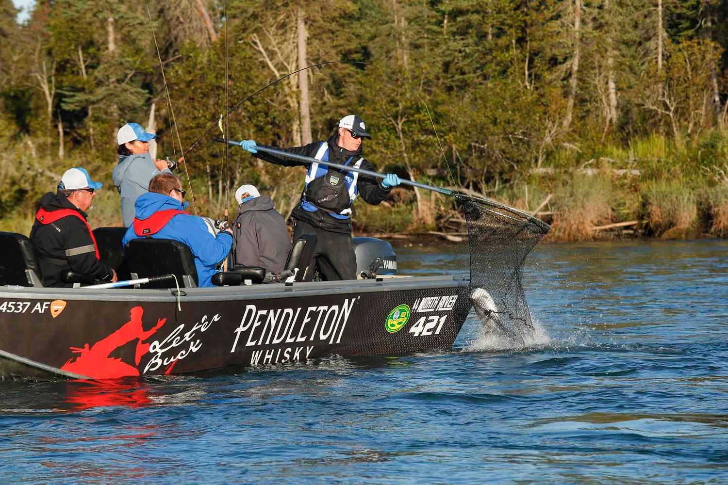 Person filleting fresh salmon on a textured black surface.
