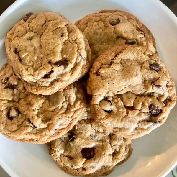 A plate with five chocolate chip cookies.