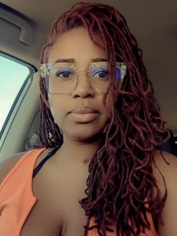 Woman with long red dreadlocks and clear glasses in car.