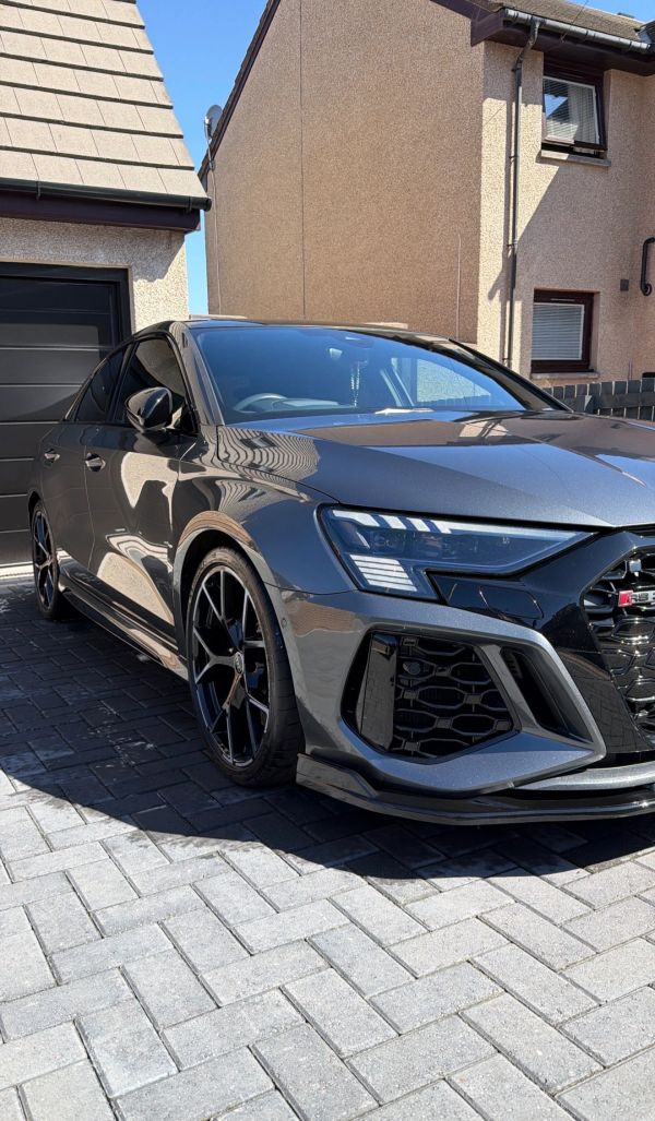 Gray Audi RS7 parked in front of a house on a sunny day.