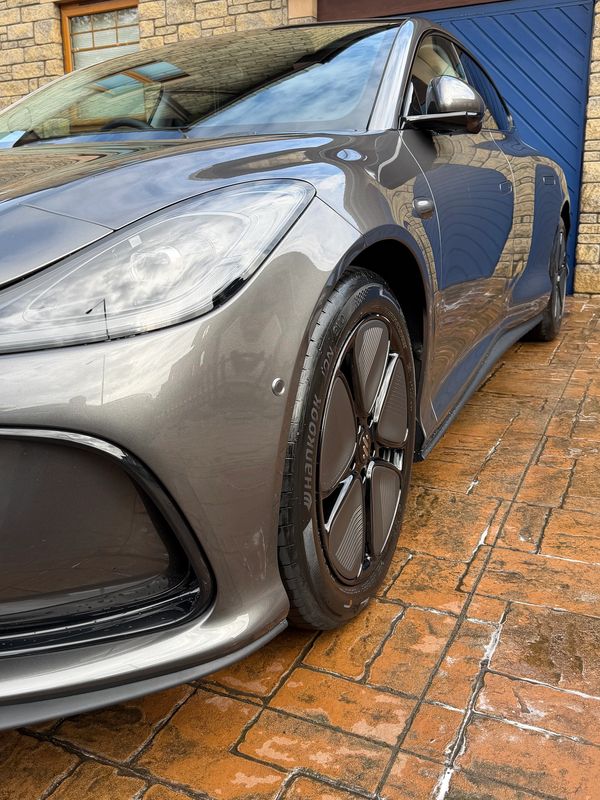 Sleek silver car parked on a brick driveway.