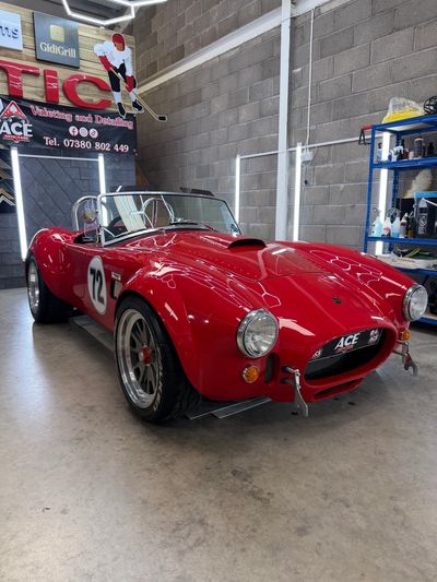 Red vintage race car with number 72 inside a garage.