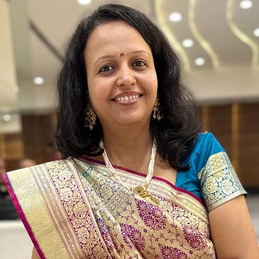 Woman smiling in a traditional silk saree with intricate designs.