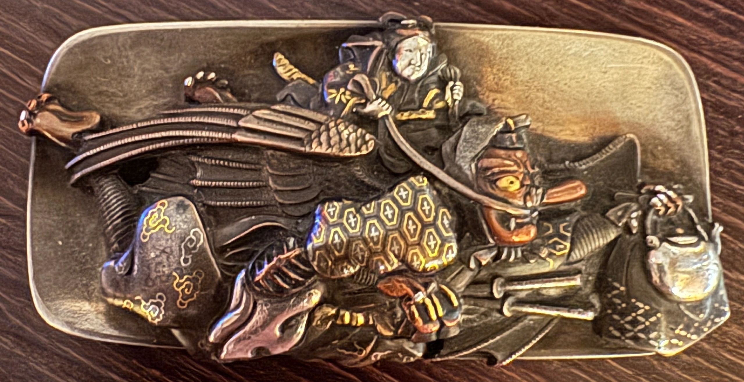 Silver & mixed metal Mae Kanagu kanamono (clasp) for a tabako ire (tobacco pouch), depicting a Tengu in flight, with elements of shibuichi, shakudo & nunome-zogan. Edo era.
