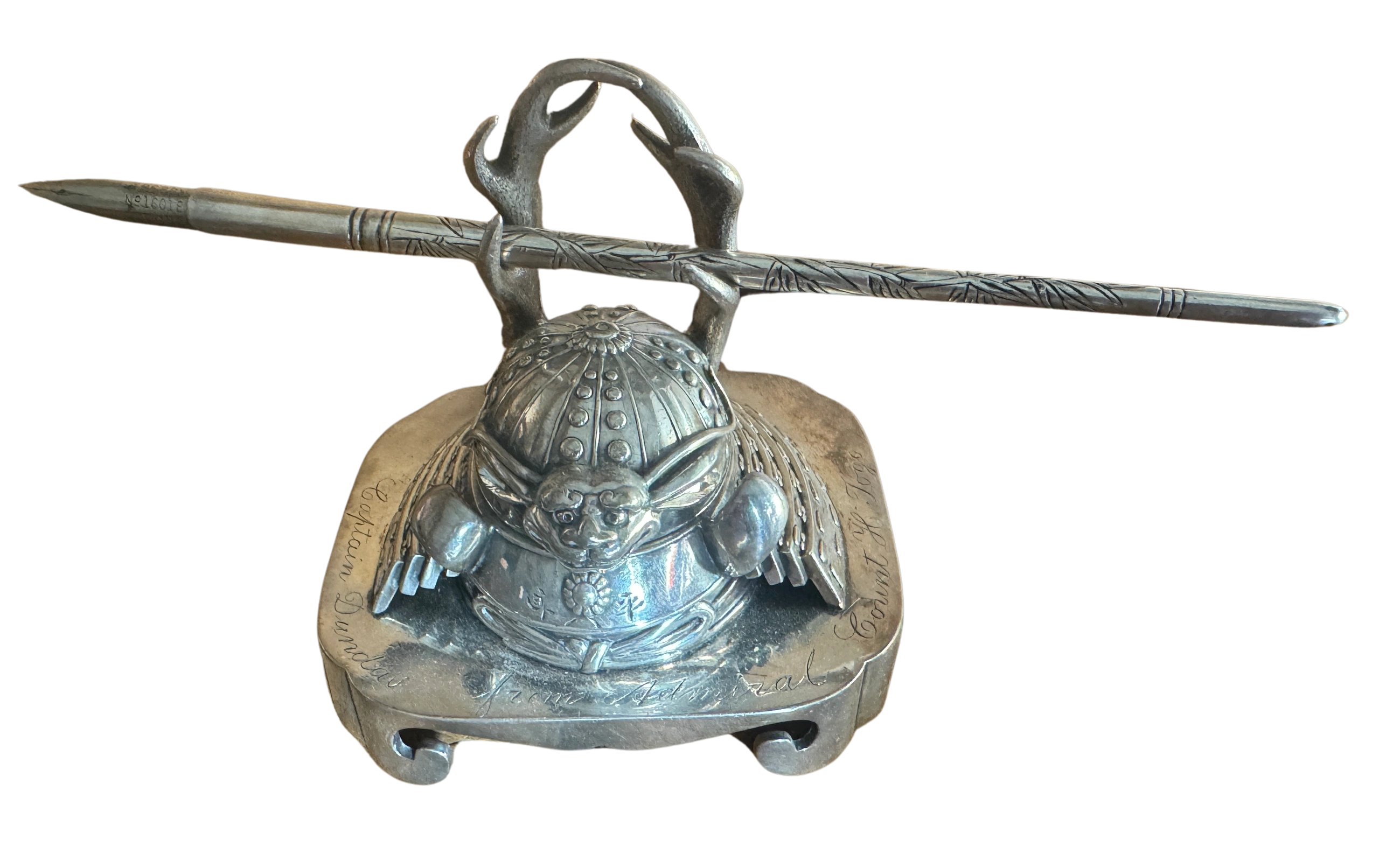 Silver inkwell formed as a kabuto (helmet), the kawagata (crest) as antlers for the pen rest, the silver pen with katakiribori decoration. Inscribed in kanji Hei-Hachi-Ro by a junikiku mon and, in Englsh: Captain Dundas from Admiral Count H. Togo Tokyo 1910. [A gift from Gensui (Marshal Admiral) Count Heihachiro Togo (1848-1934) to Royal Navy captain  (later Admiral) Charles Hope Dundas (1859-1924)]. Meiji era.