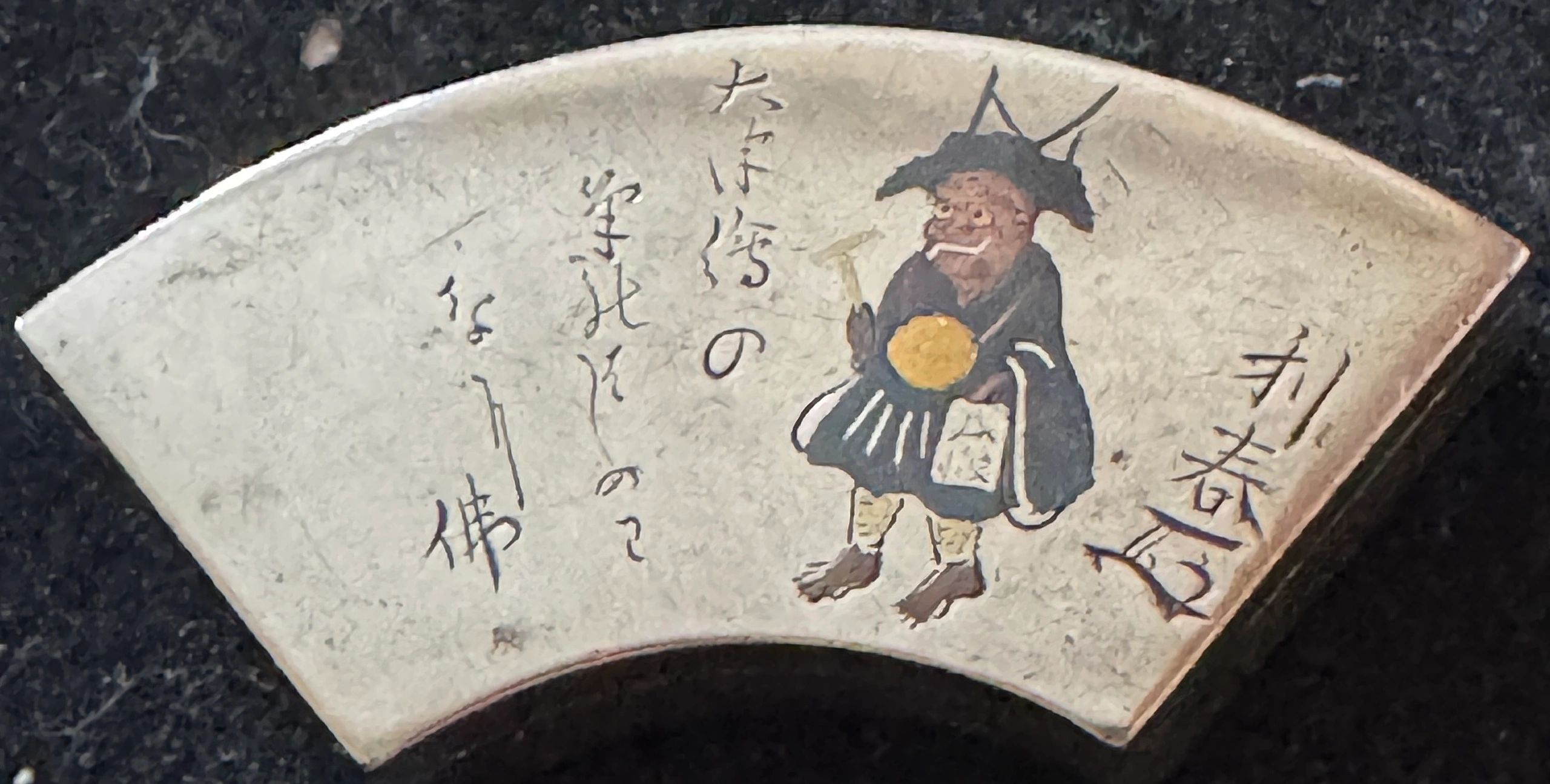 Silver kogo depicting Oni no Kannebutsu (Oni in Winter training) in Takabori & Iroe gold, silver, copper & shibuichi. The inrobuta (flush fitting) lid is incised with a Haiku (poem) by Matsuo Basho (1644-94): “For an otsu-e (folk painting) the first stroke of the brush should draw which Buddha?” Signed Siufu ju Ichiyoken Toshiharu (Toshiharu, resident of Mito) with personal kao. Edo era.