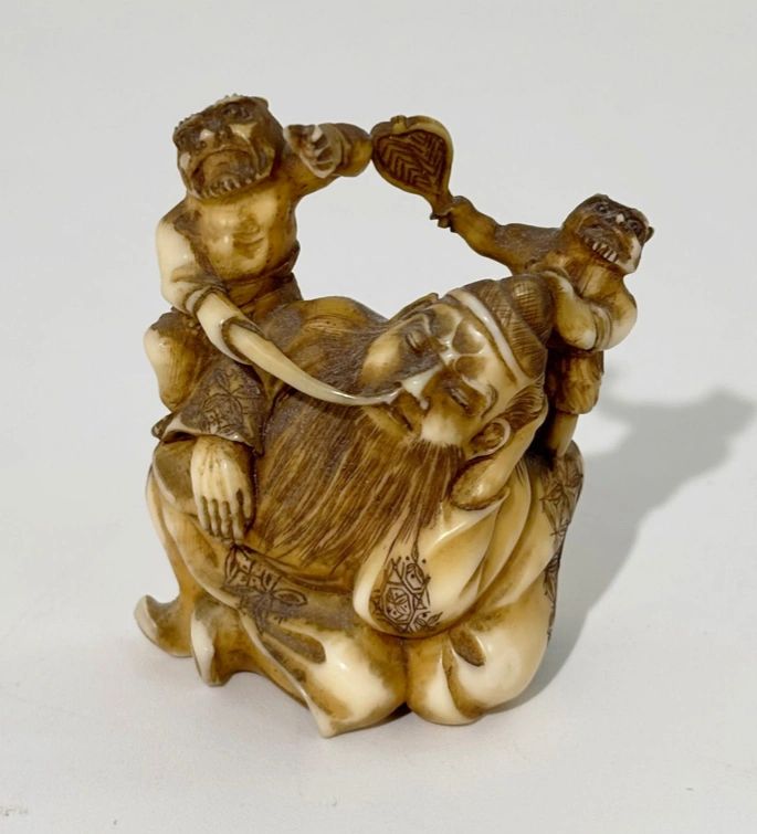 Walrus ivory Okimono depicting two onis taunting Jurojin. Signed Gyokuichi, Edo era.