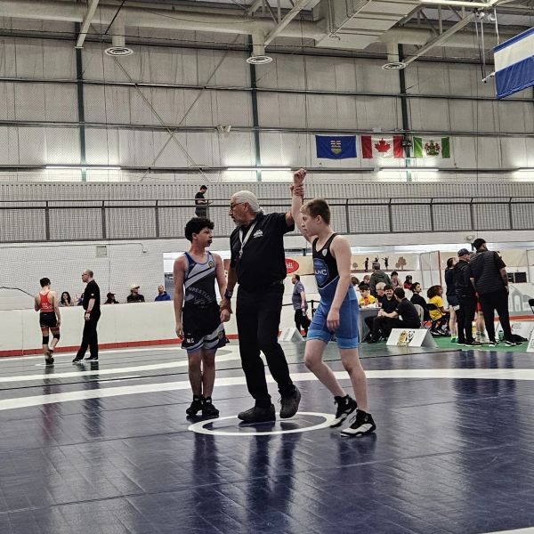 Referee raises the winner's hand after a youth wrestling match.