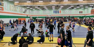 High school wrestling tournament with multiple matches in progress.