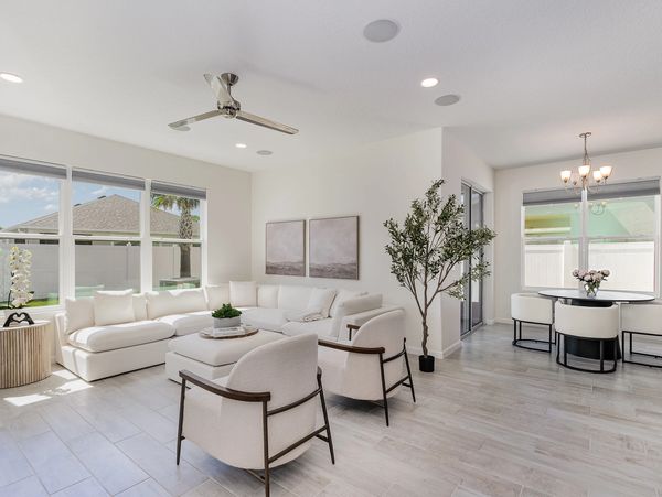 Bright living and dining area with modern white furniture and large windows.