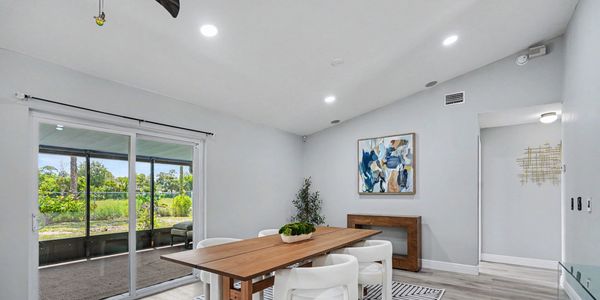 Modern dining area with wooden table and white chairs.