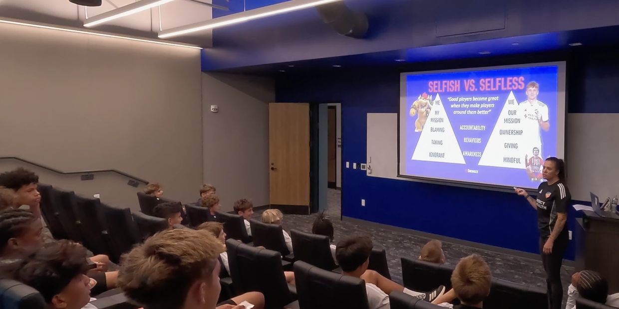 Coach giving a motivational talk to young athletes in a classroom.