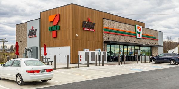Exterior view of a 7-Eleven convenience store with cars parked outside.