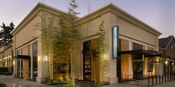 Modern corner building with large windows and outdoor seating.