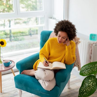 woman with curly hair writing in a journal