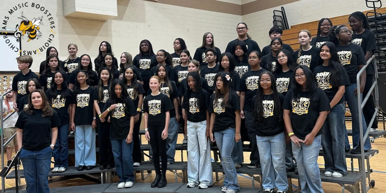Group photo of a school choir and band members in matching shirts on risers.