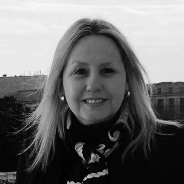 Black and white portrait of a smiling woman outdoors.